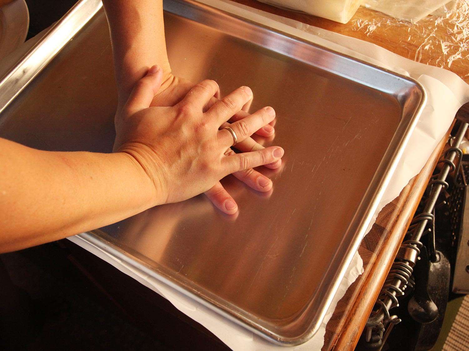 Pressing one baking sheet onto another to flatten bean-cashew puree.
