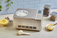 A top-down view of a whynter compressor ice cream machine on a countertop surrounded by ice cream accessories and toppings