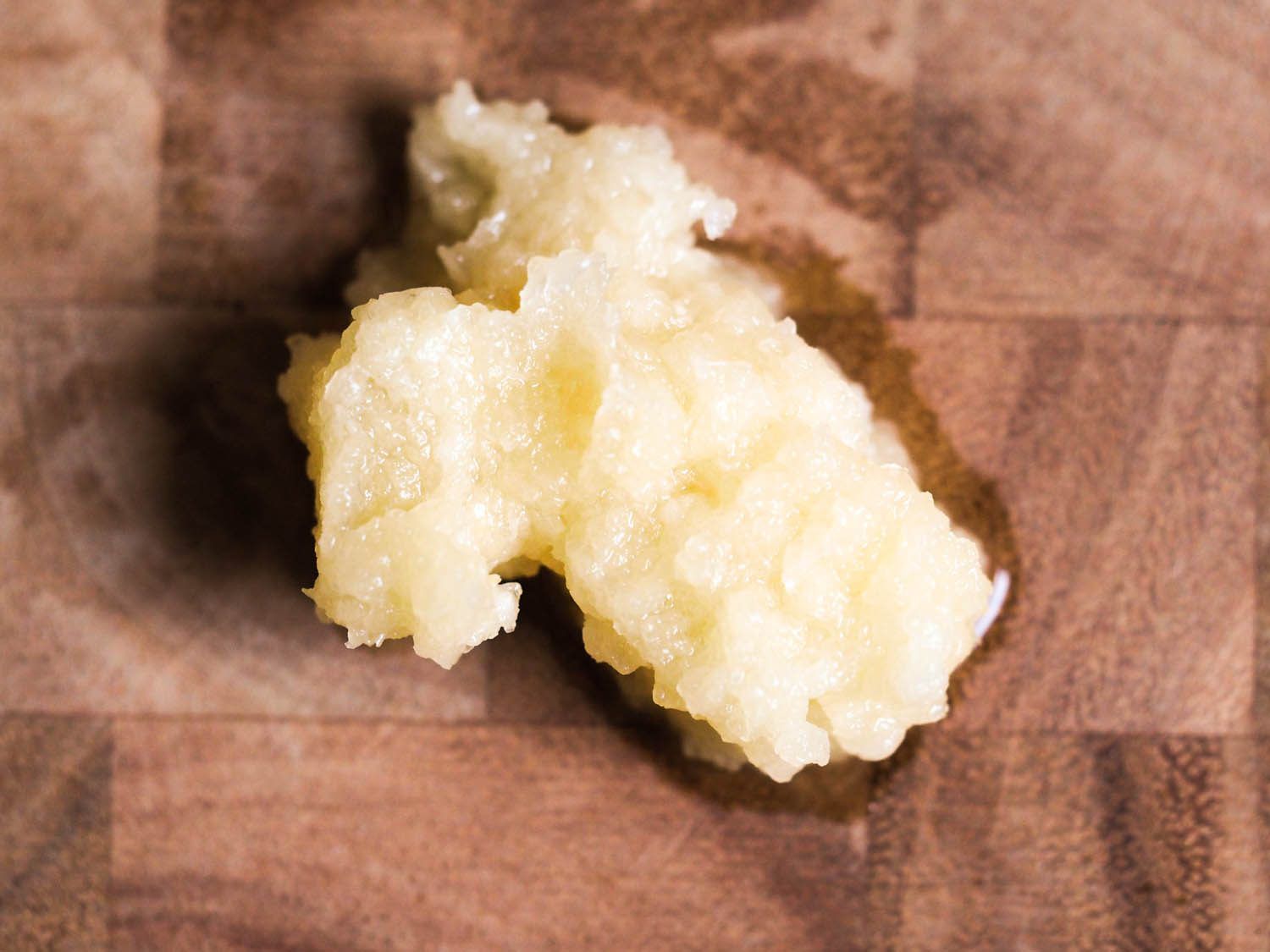 Crushed garlic on a cutting board.