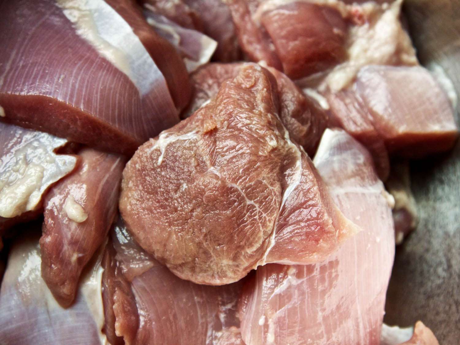 Closeup of raw boneless turkey thighs, cut into 2-inch pieces.