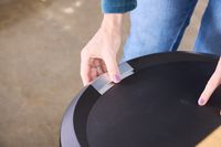 A person unlatches the simplehuman Semi-Round Step Trash Can