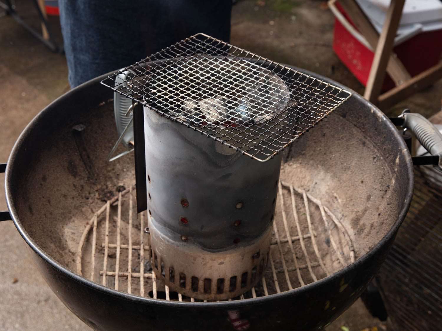 A wire rack set over a chimney starter full of coals on a kettle grill