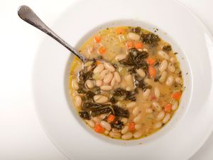 Overhead view of Tuscan white bean soup in a wide, shallow soup bowl.
