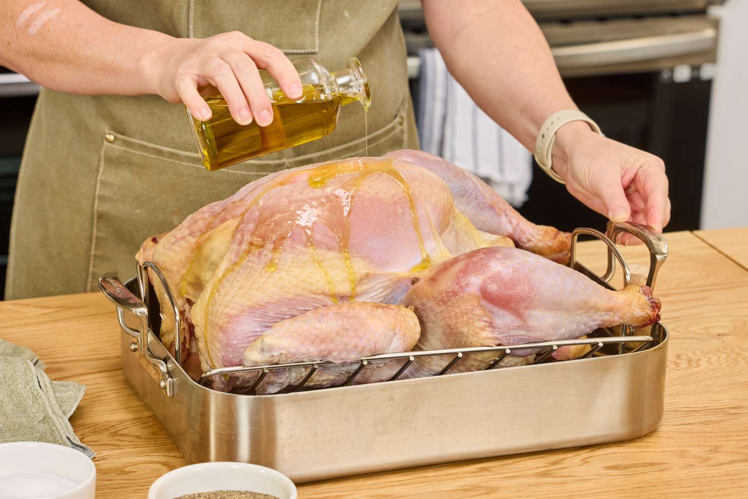 A person pouring olive oil onto a raw Grassland Beef Pasture Raised Turkey