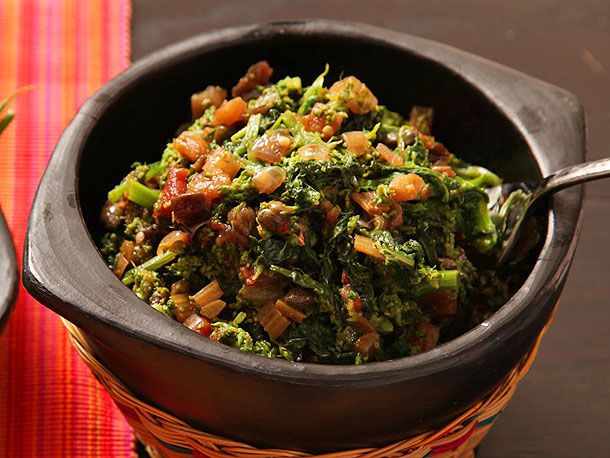 A black bowl of broccoli rabe with a flavorful caponata-style sauce.