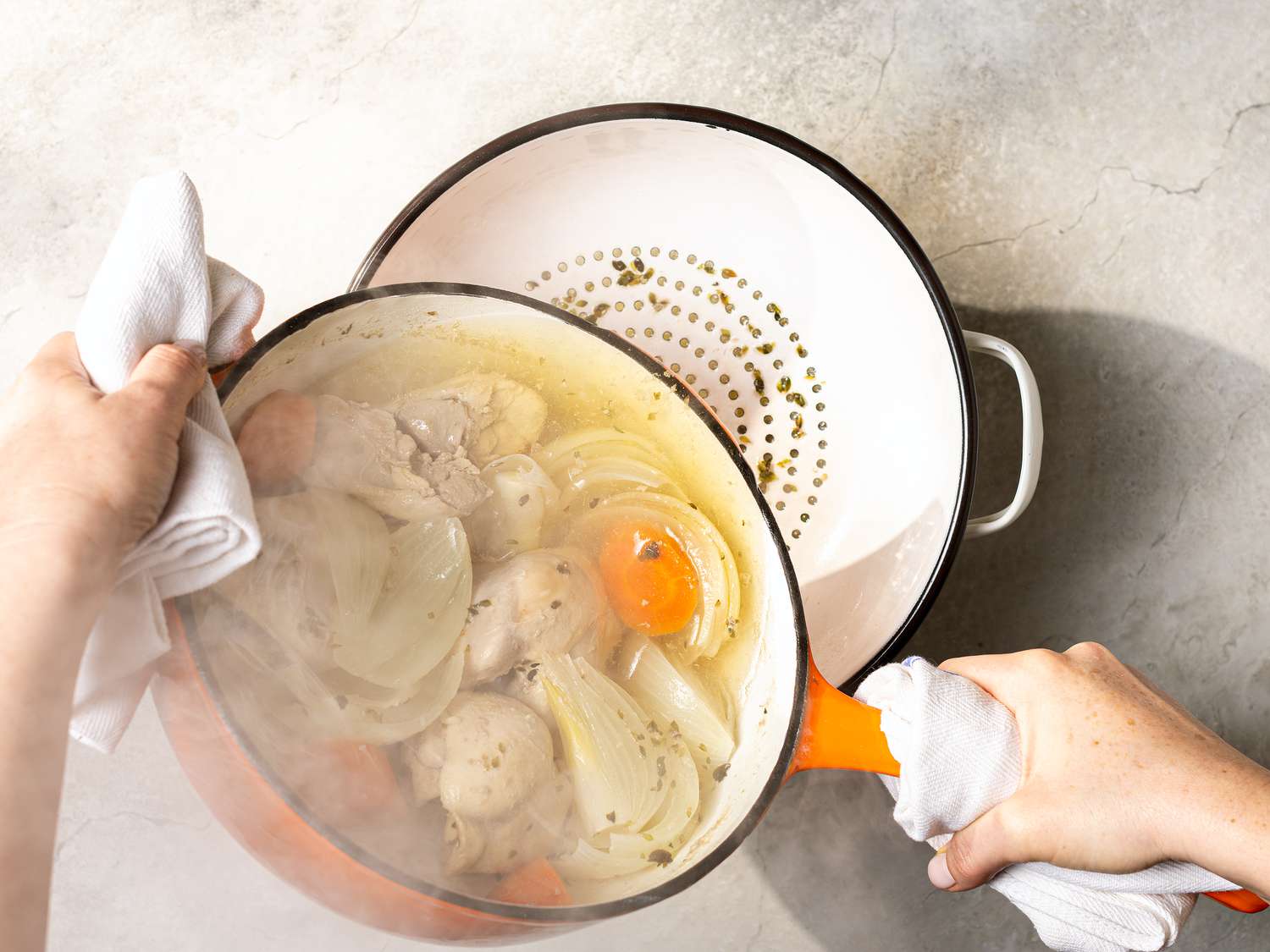 Poached chicken being drained through a colander 