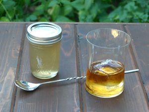 A jar of homemade gomme syrup next to a cocktail