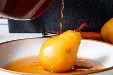 Pouring sauce over poached pear