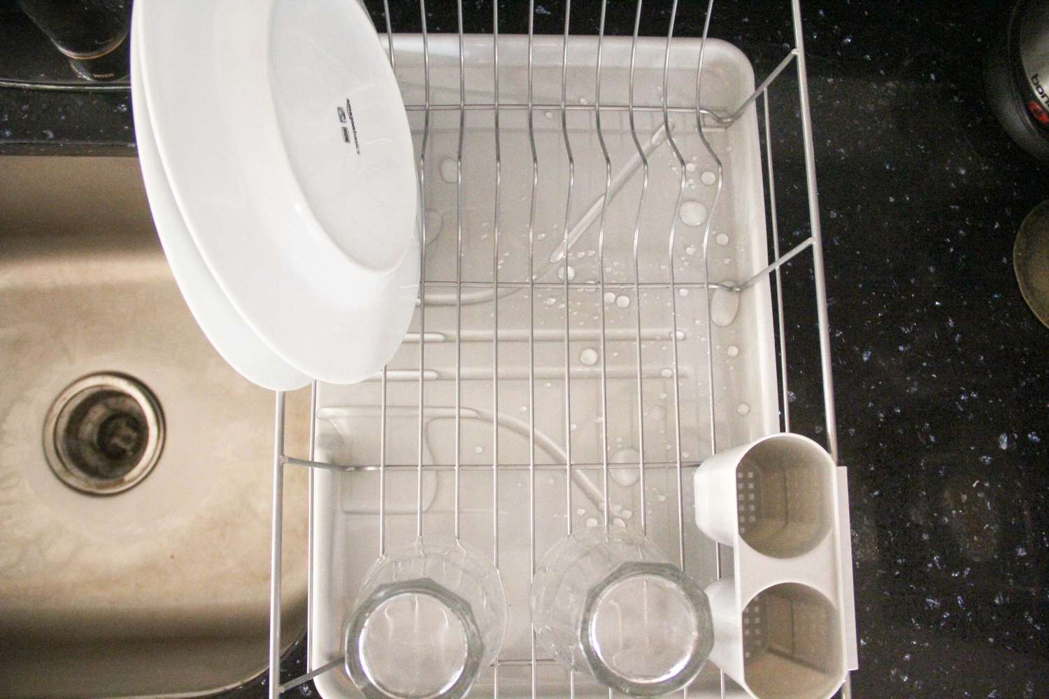 A dish rack drying dishes near a kitchen sink. 