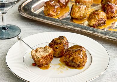 Turkey meatballs glazed with maple mustard served on a white plate with a serving tray in the background
