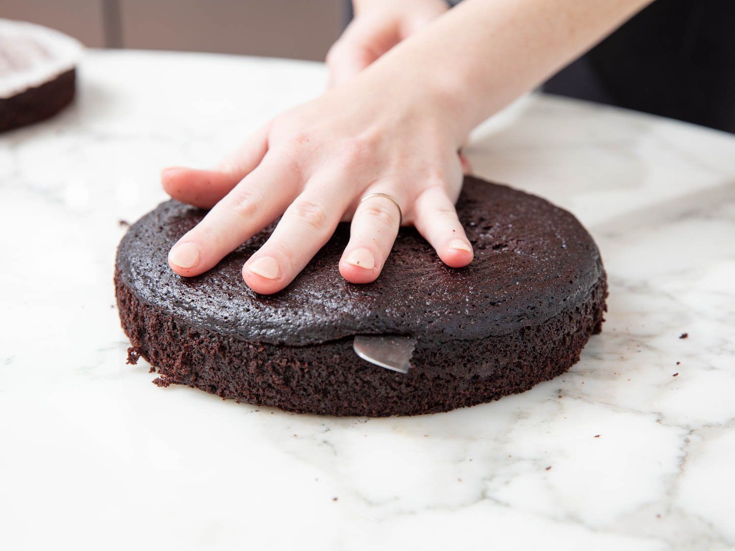 Leveling a chocolate cake with a serrated knife.