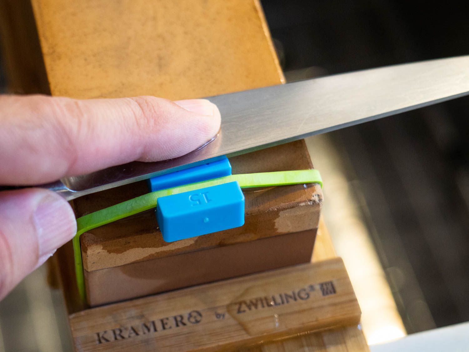 A knife is held atop the angle guide on a whetstone, helping keep each sharpening stroke consistent