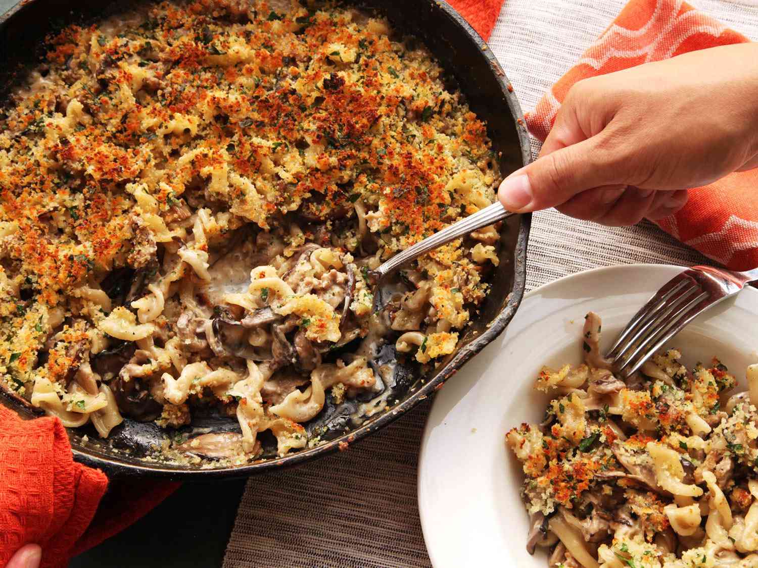 Serving up crispy baked pasta with mushrooms,sausage, and parmesan cream sauce out of a cast iron skillet. 
