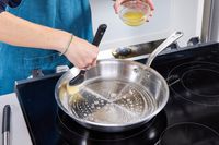 A person greases the inside of the Made In 12-Inch Stainless Steel Skillet