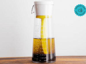 The Emulstir salad dressing mixer on a wooden table in front of a white wall.