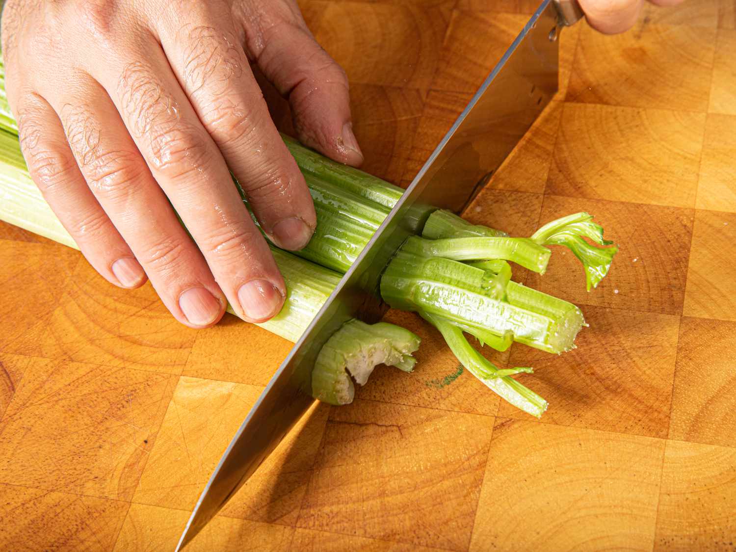 Overhead view of cutting off tops of celery