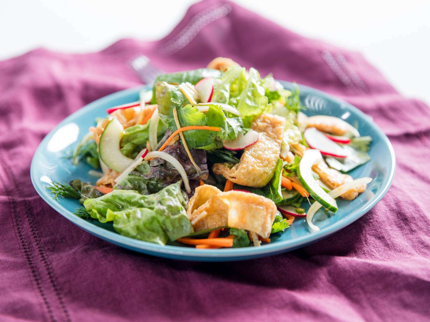Closeup of the vegan tofu and herb salad, served on a table draped with fuchsia-colored cloth.