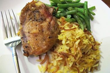 Closeup of skillet chicken with homemade Rice-A-Roni and green beans, served on a white plate.
