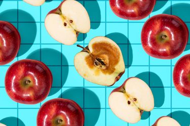 Red apples arranged on a blue grid background some cut in half to reveal their interiors