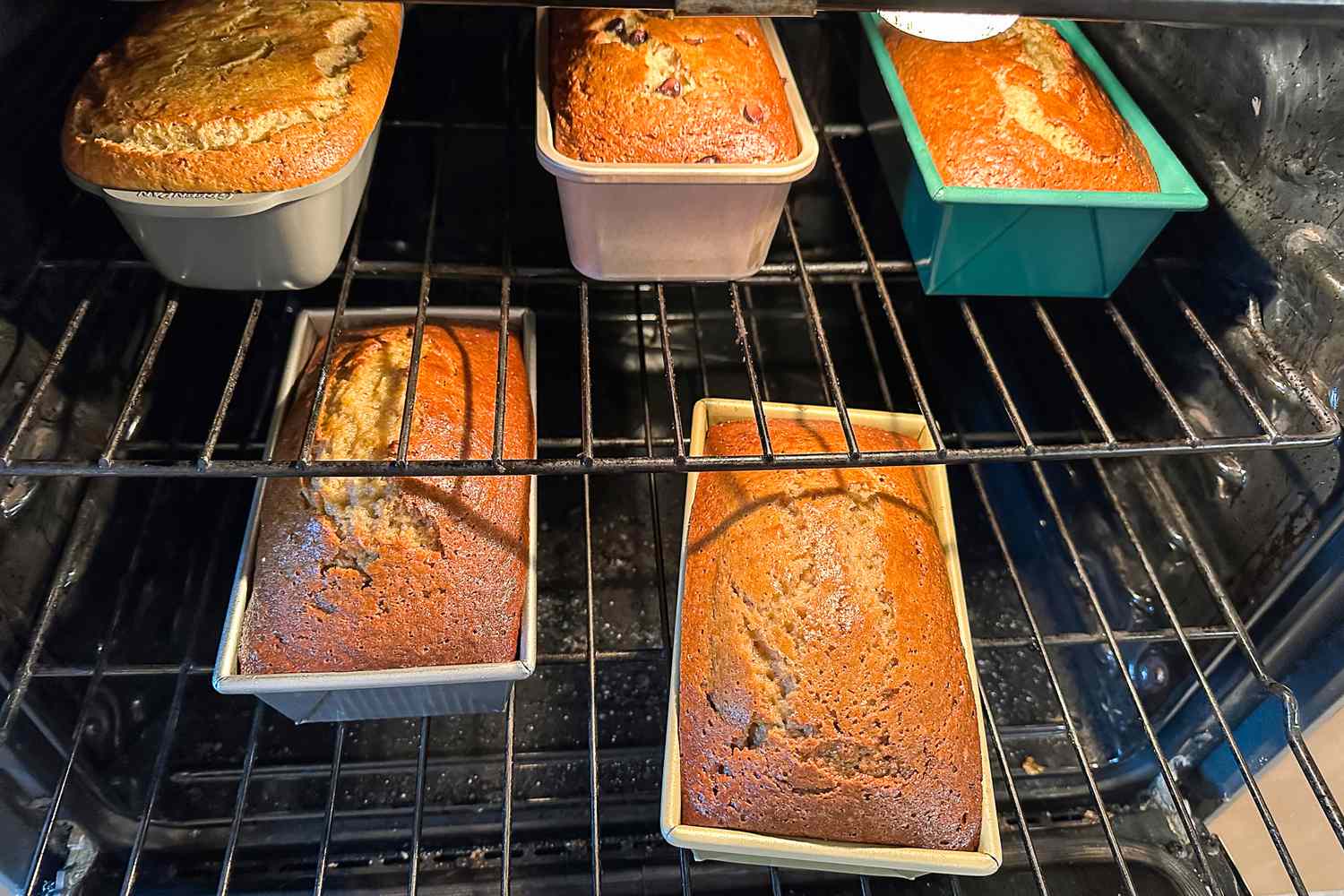 Multiple loaf pans with baked bread on oven racks