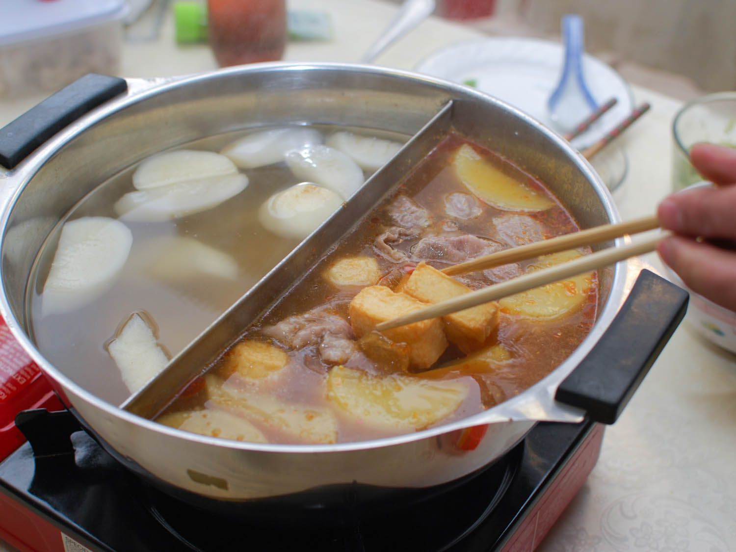 Dipping fried tofu into a Chinese hot pot.