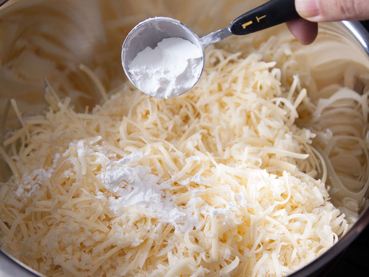 Cornstarch being added to cheese