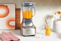 Orange liquid is blended in the Breville Stainless Steel Super Q Blender