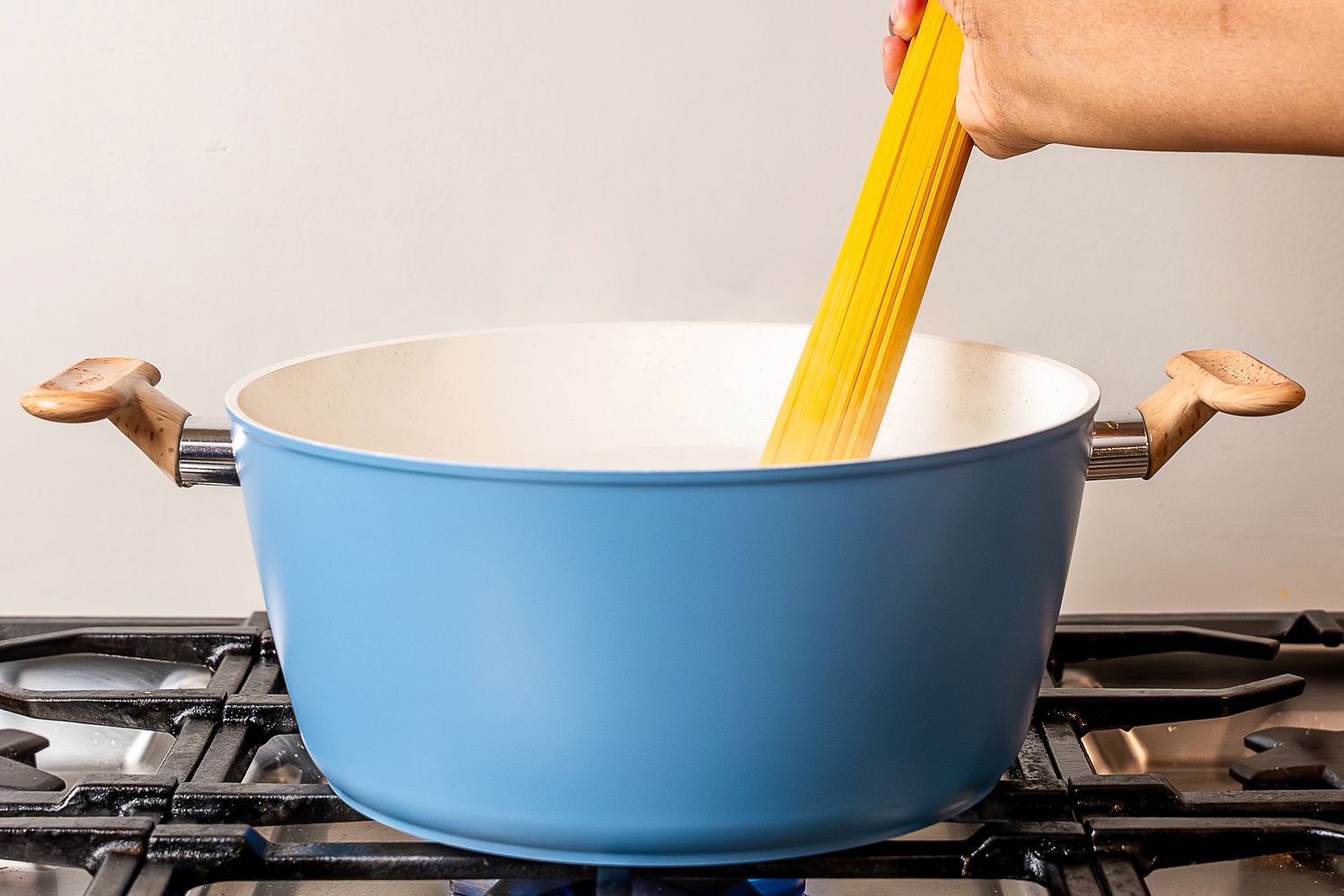 A hand placing pasta into a pot from the GoodCook Ceramic Titanium-Infused Cookware Set