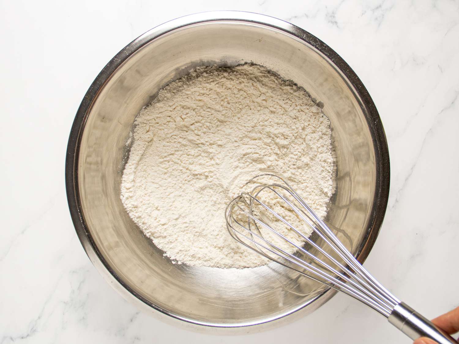 whisking together dry ingredients in a metal bowl. 