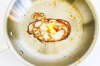 An egg cooking in a pan from the All-Clad D3 3-Ply Stainless Steel Cookware Set 10 Piece