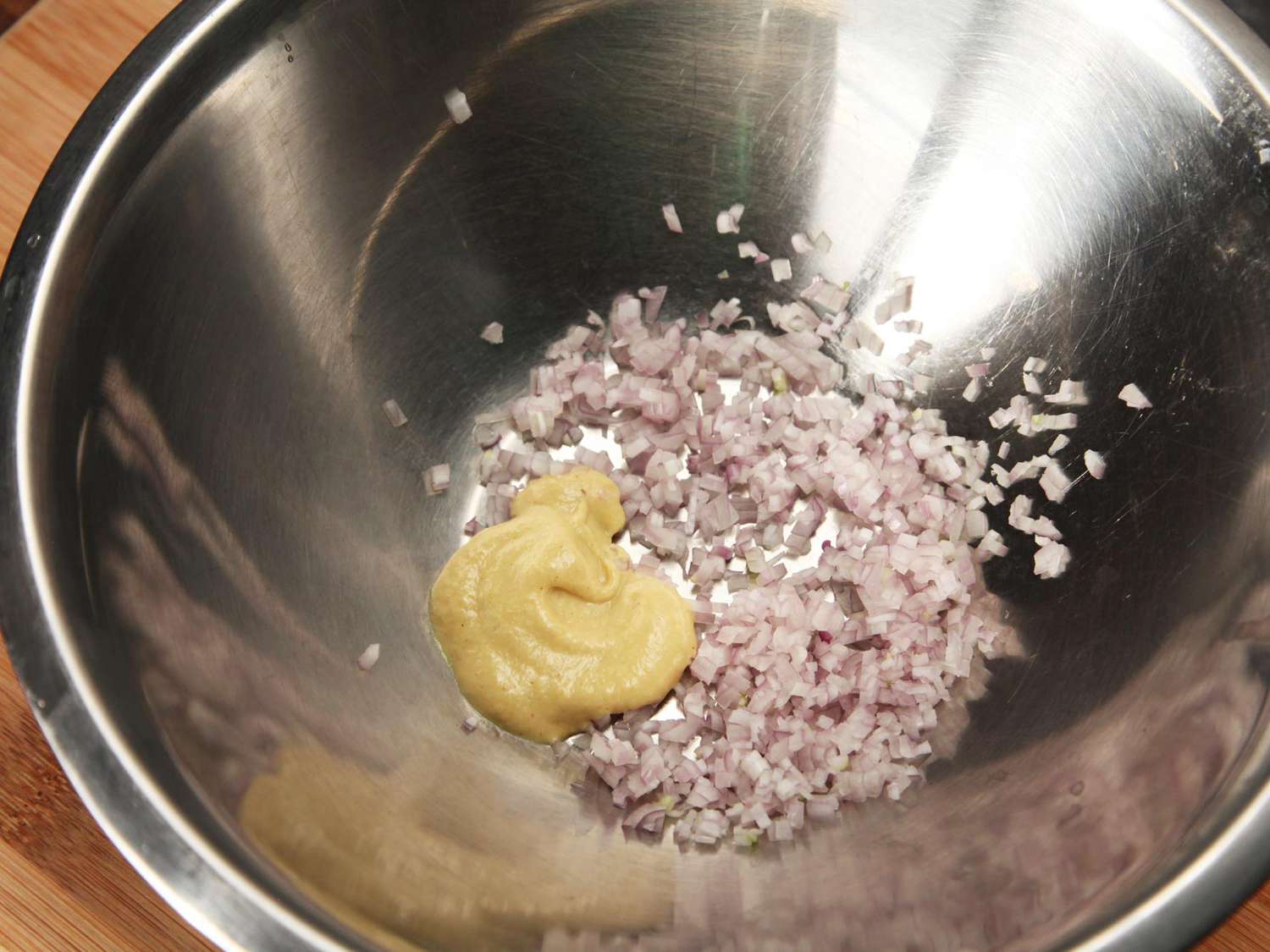 Minced shallot and dijon have been added to a mixing bowl.