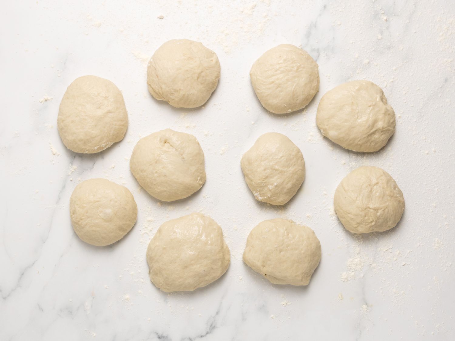 Ten dough balls evenly arranged on a white surface