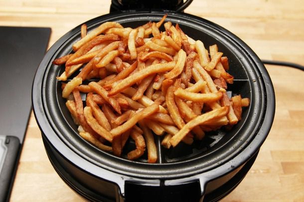 An open waffle iron, covered in a heap of fries.