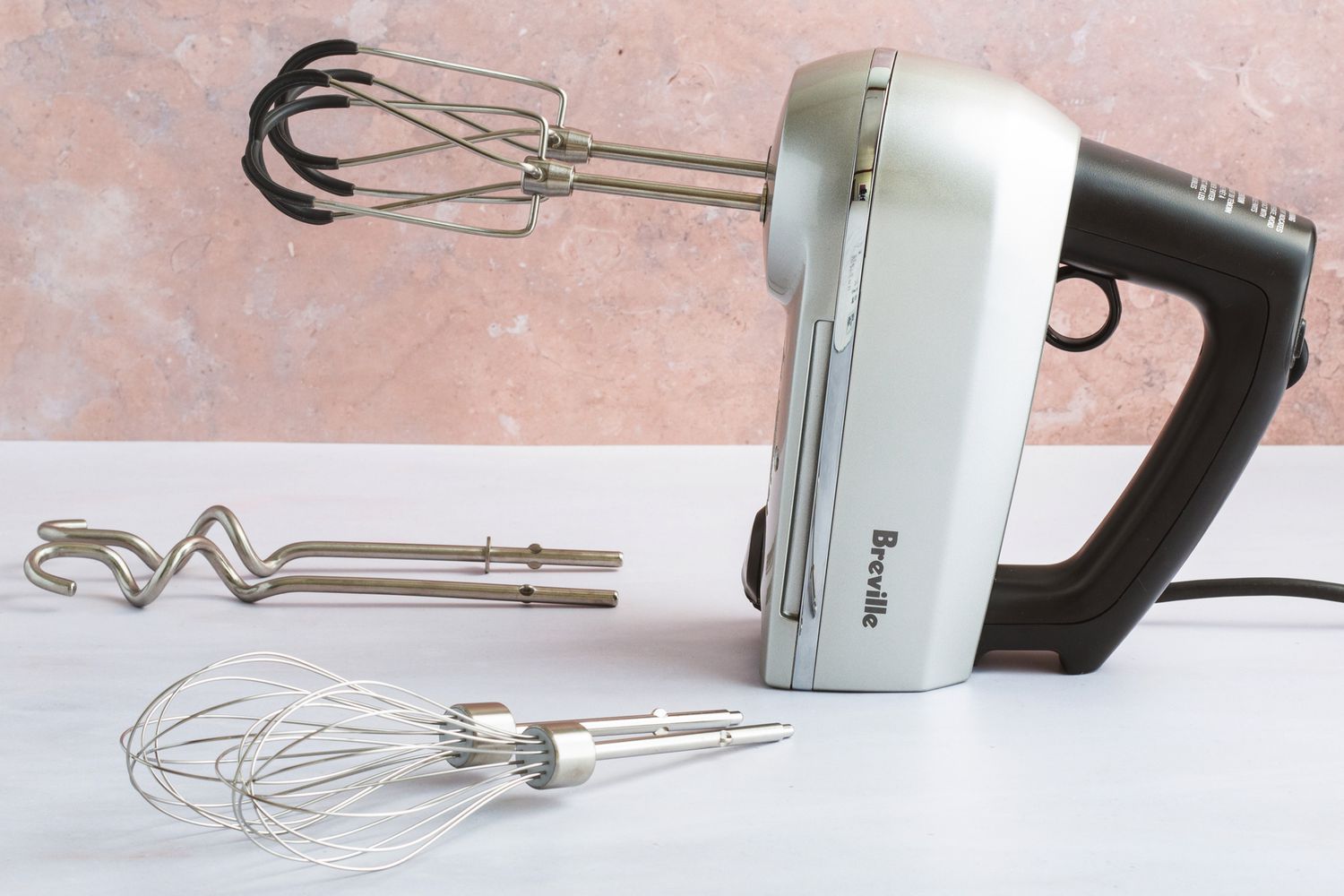 The Breville hand mixer on a white kitchen countertop.