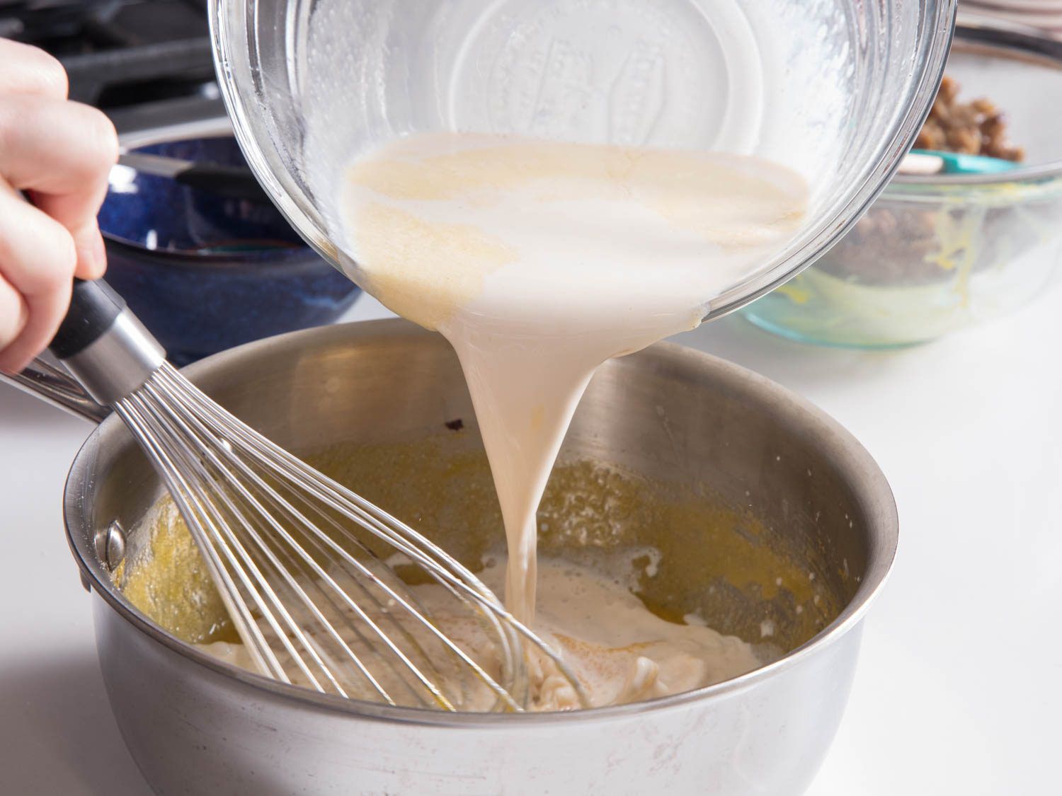 Whisking warm hazelnut milk into eggs and sugar in a saucier