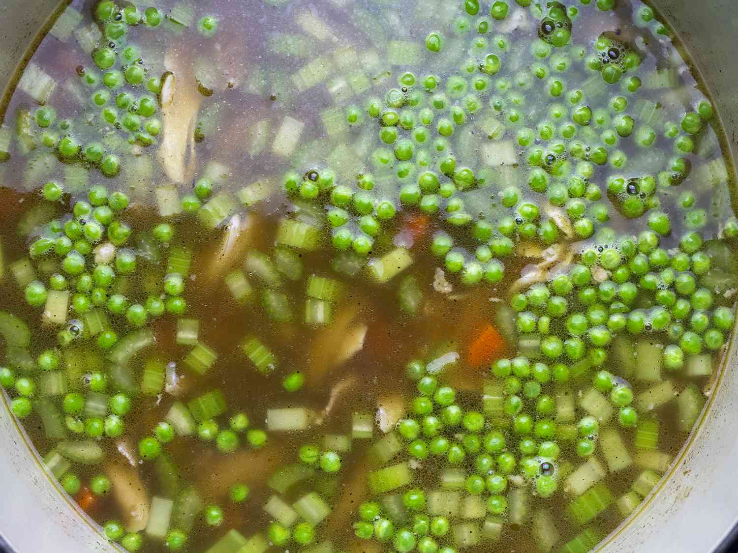 Pea-laden chicken and rice soup in a pot.