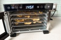 The Cosori food dehydrator with apple chips drying on its racks