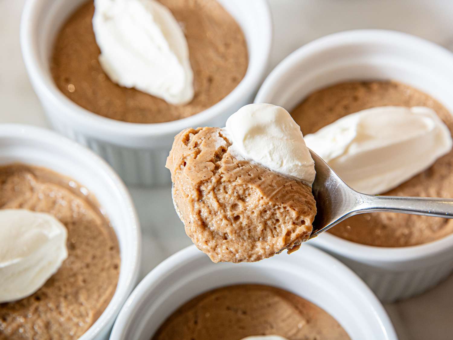 Bowls of pudding with whipped topping, spoon holding a serving