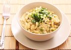 Green chile chicken mac and cheese, served in a white bowl and garnished with scallions and cilantro.