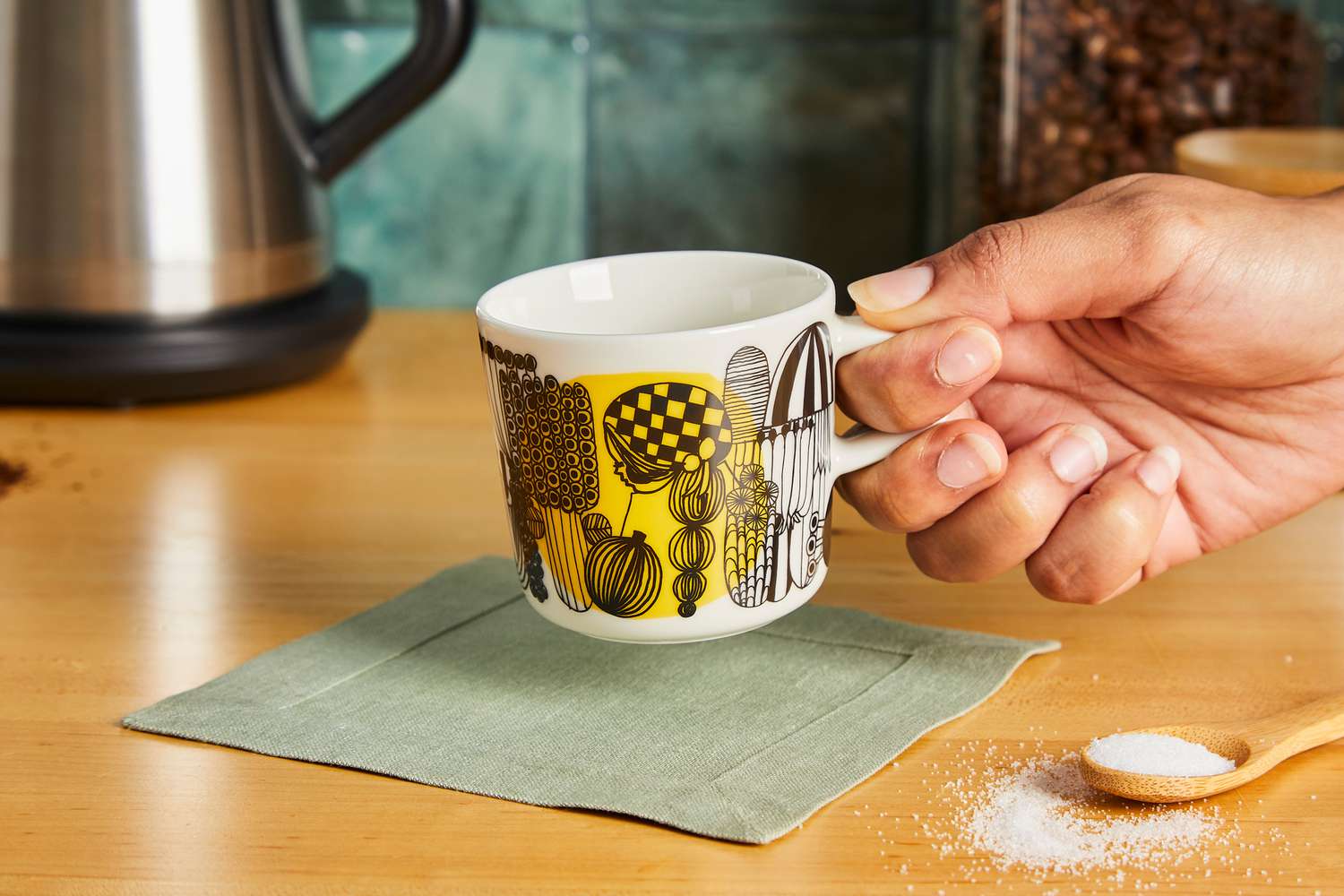 A person picking up the Marimekko coffee mug.