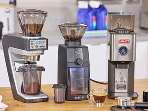 Three espresso grinders on a kitchen counter