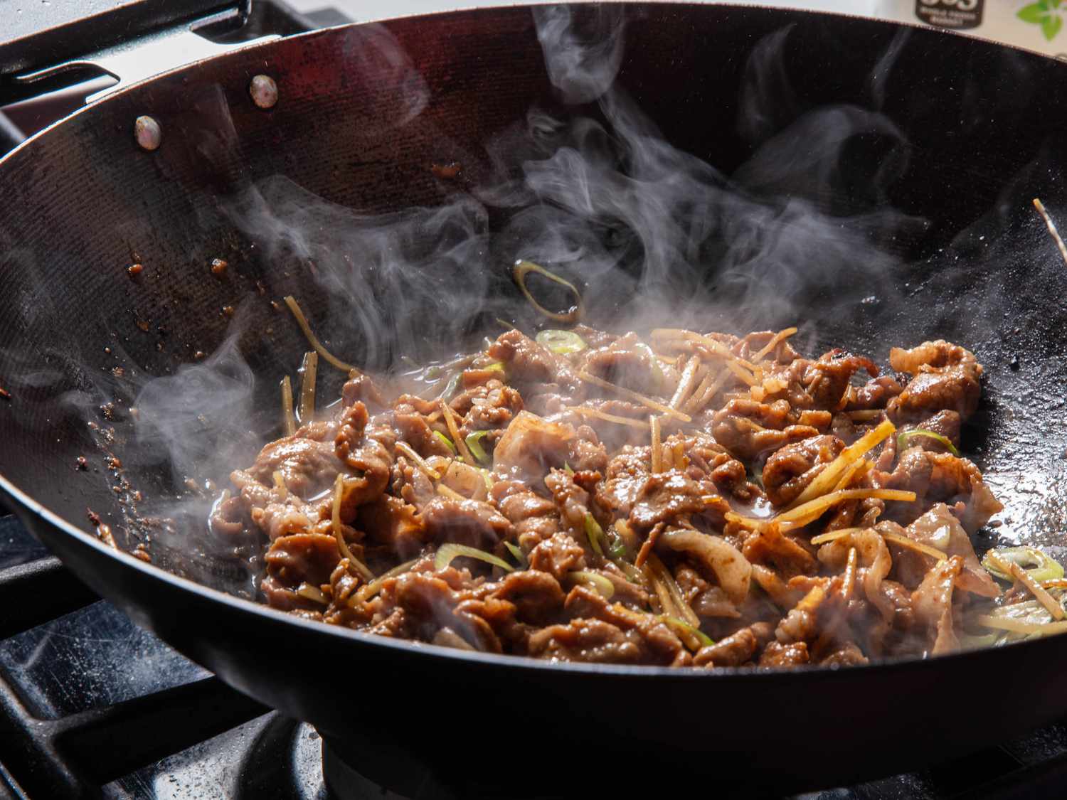 Cooked pork ginger steaming in the bottom of a wok