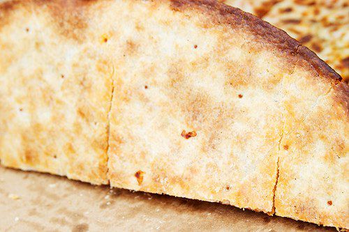 The bottom of a Domino's pizza showing a browned crust with crispy dark brown edges. 