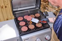 A person flipping patties on the Weber Spirit E-310 Gas Grill