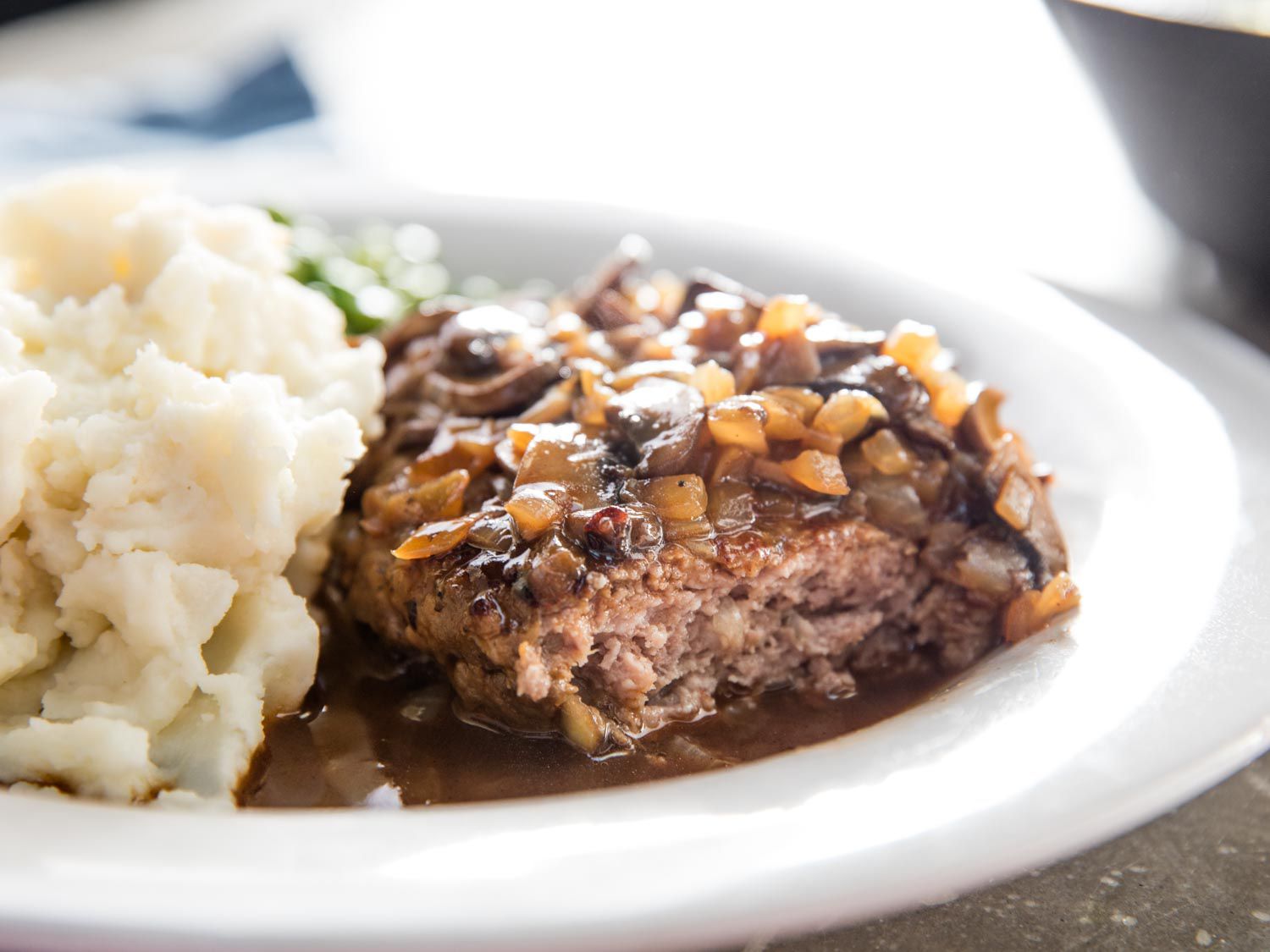 Close-up of the Salisbury steak. A bite has been taken, revealing the moist interior of the patty.