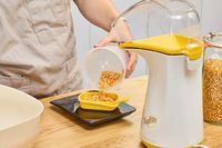 A person measures kernels before popping in the Presto Poplite Hot Air Popper