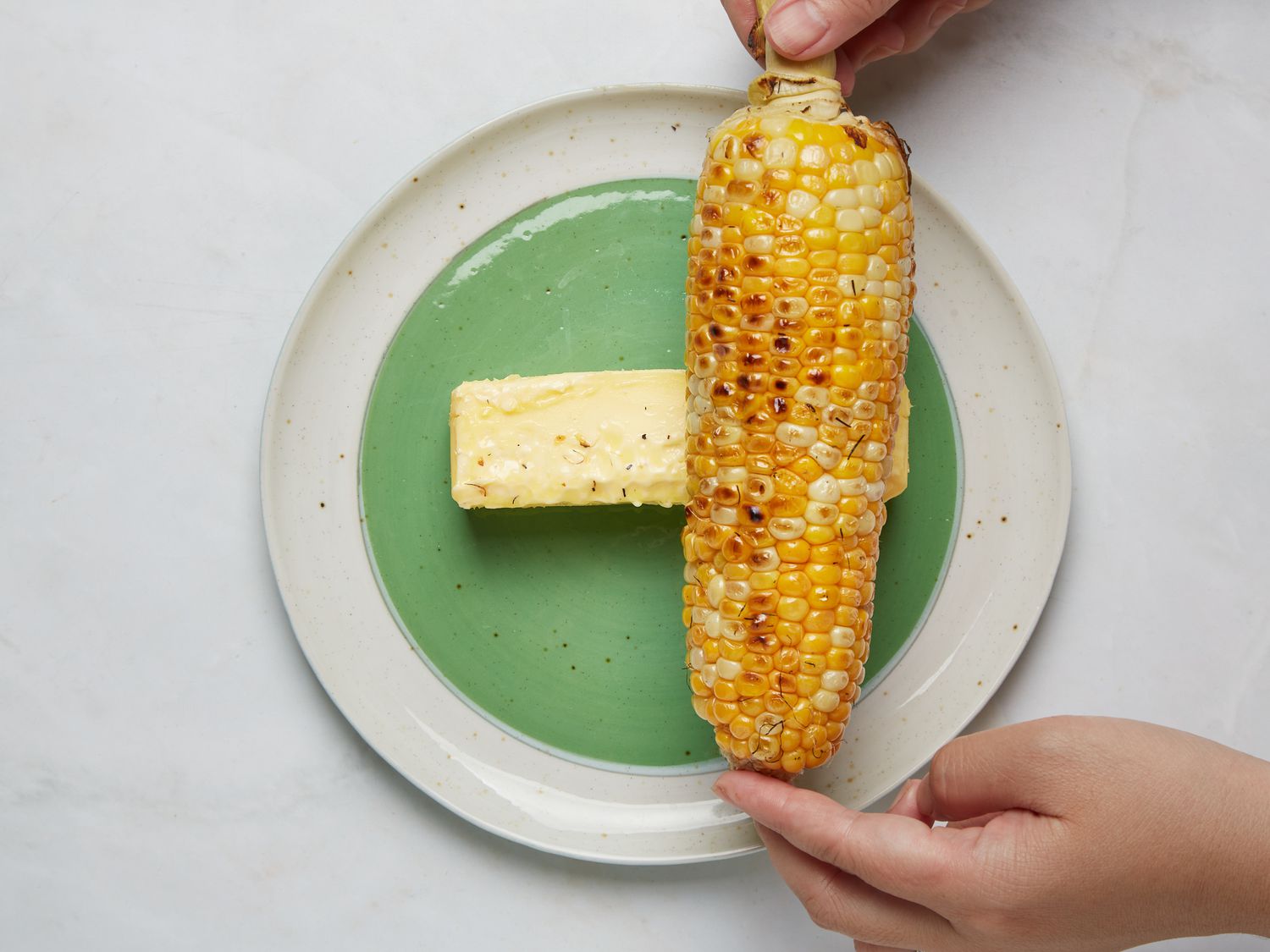 Grilled corn on a plate with a stick of butter