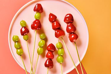 Tanghulu sticks on a pink circular plate, with a pink and orange background