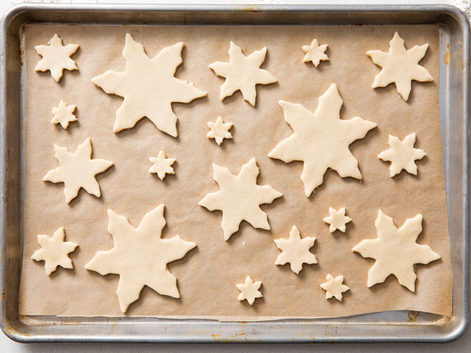 Sugar cookies on a piece of parchment in a baking sheet.