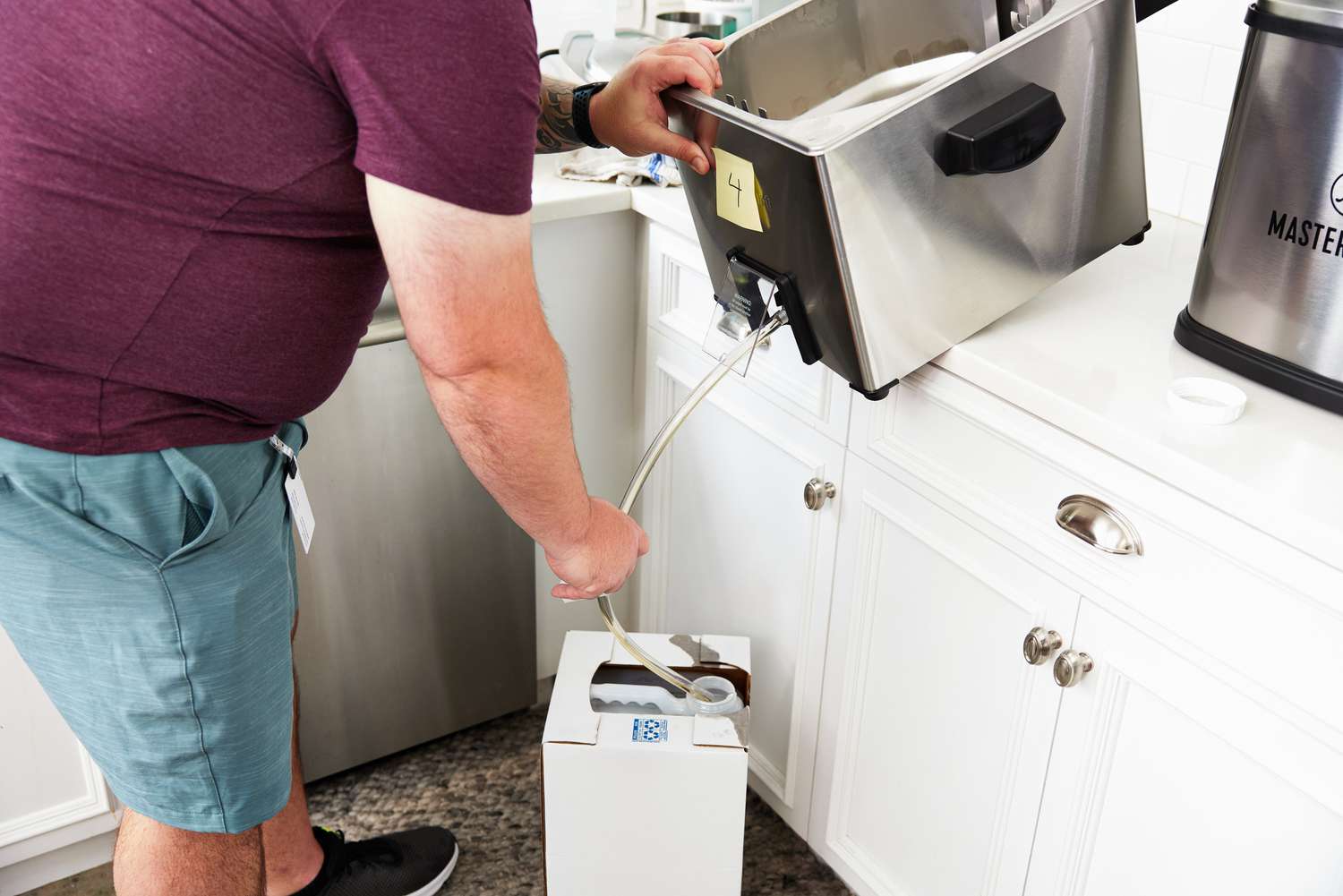 A person draining oil out of a deep fryer